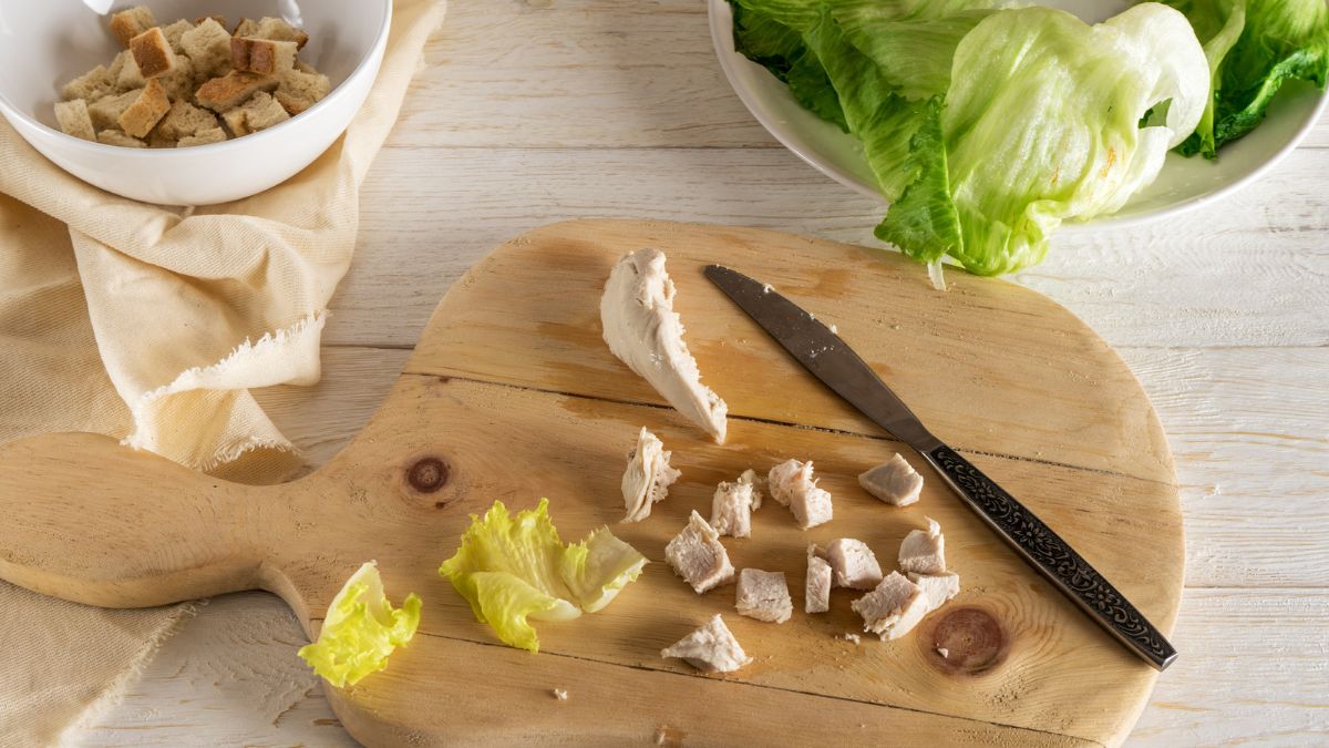 making Caesar salad, chopping chicken