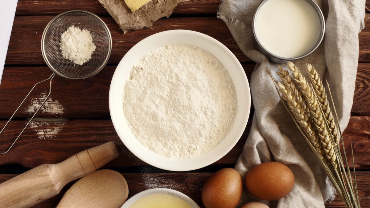 Pancake ingredients lined up on a dark brown wooden table with half and half instead of milk