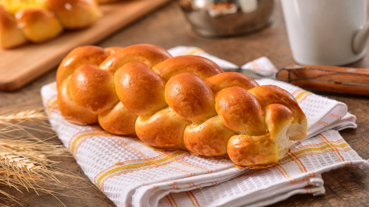 fresh out of the oven, a brioche bun served on a kitchen towel with another one back in the background